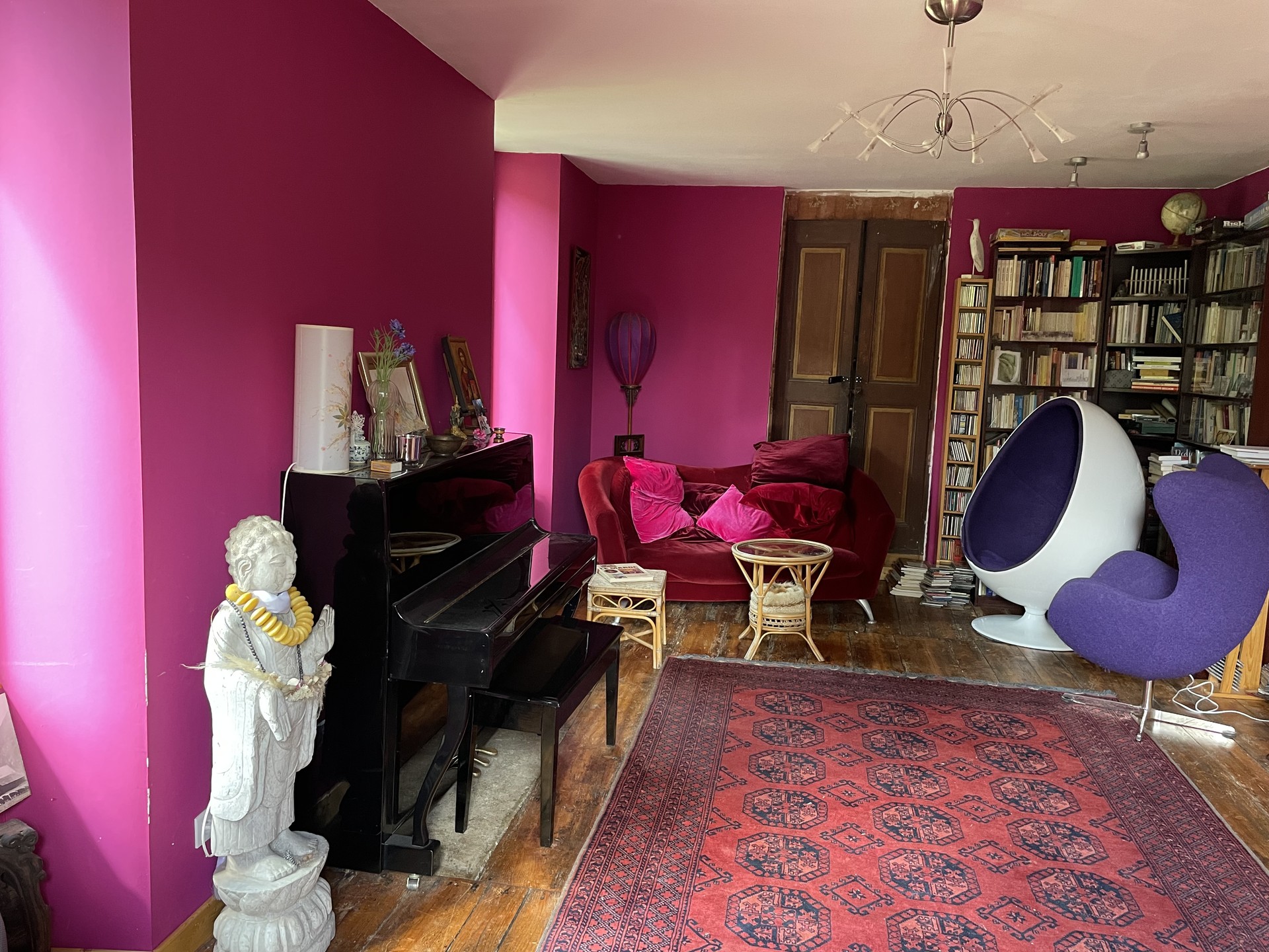 Pièce à vivre de la maison : piano noir, canapé et bibliothèques