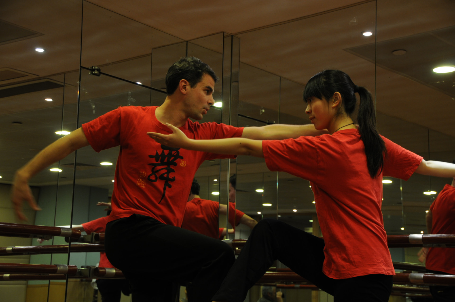 Deux danseurs en t-shirts rouges pratiquant le Qi danse dans une salle